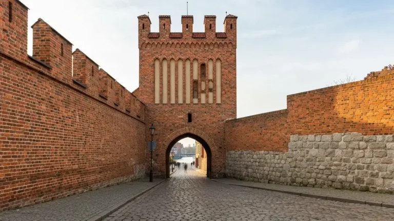 Brama Żeglarska w Toruniu od strony Wisły, z gotycką cegłą i brukowaną ulicą Żeglarską