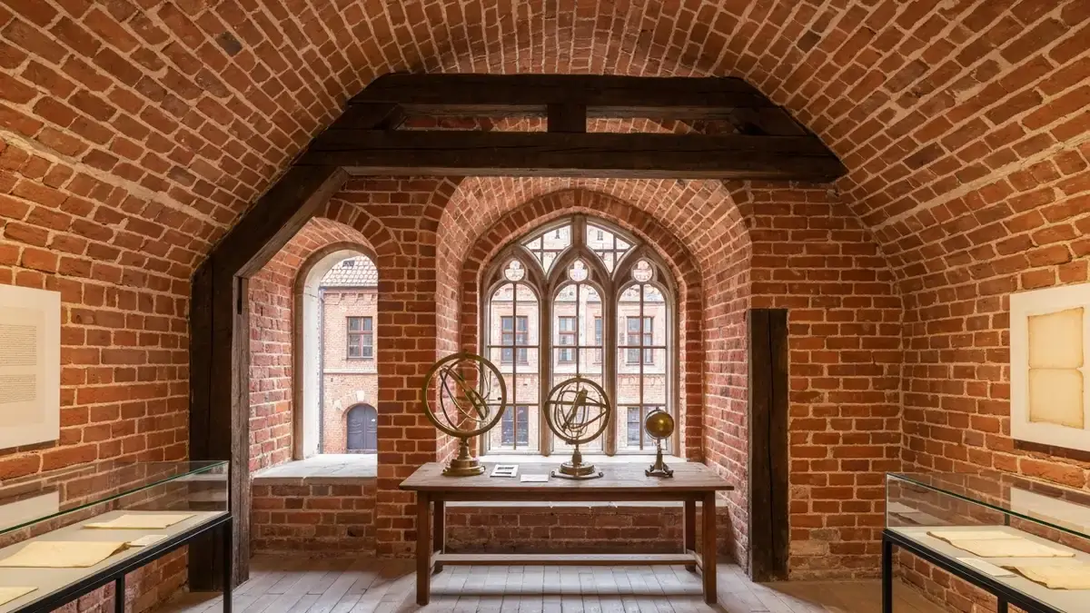 Wnętrze gotyckiej kamienicy w Toruniu z instrumentami astronomicznymi i ceglaną architekturą