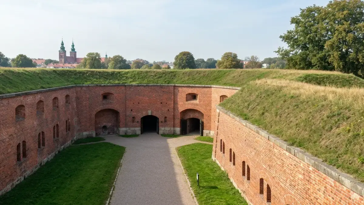 Ceglany fort Twierdzy Toruń z wałami ziemnymi i ścieżką w świetle dnia