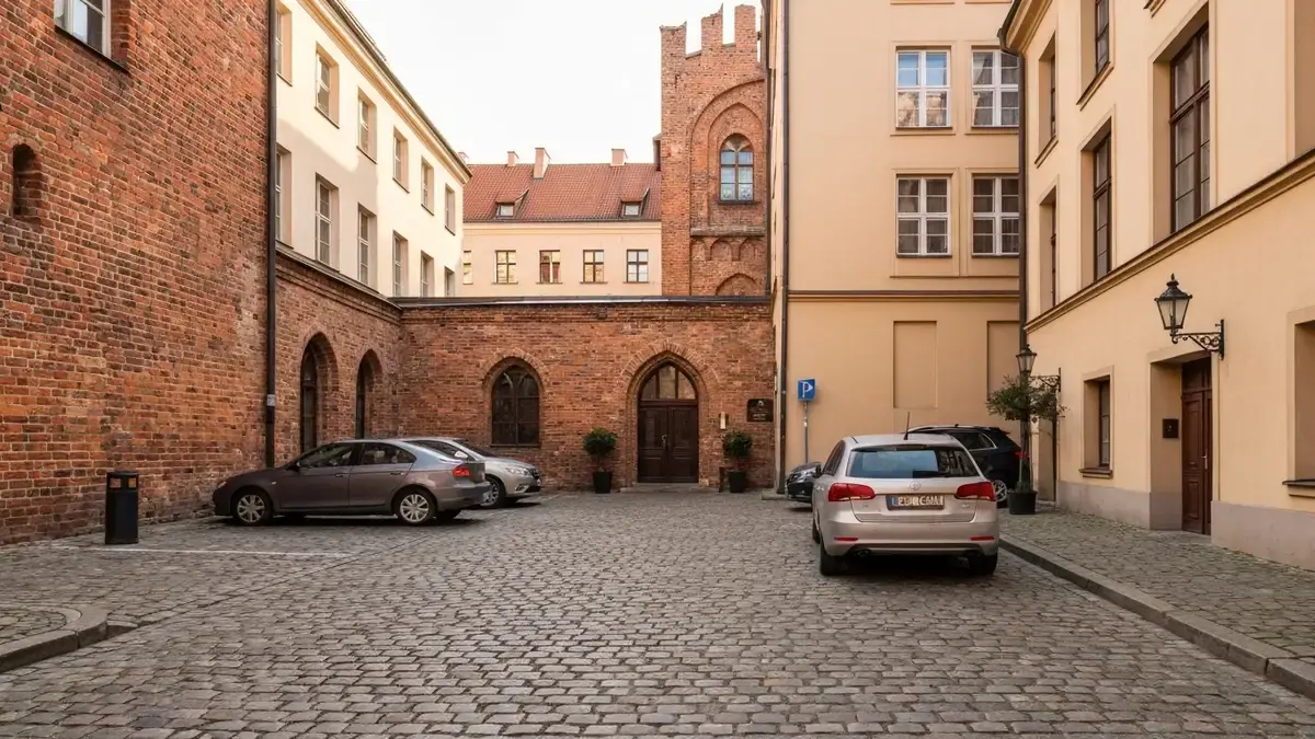 Hotelowy parking przy brukowanej ulicy blisko toruńskiej Starówki